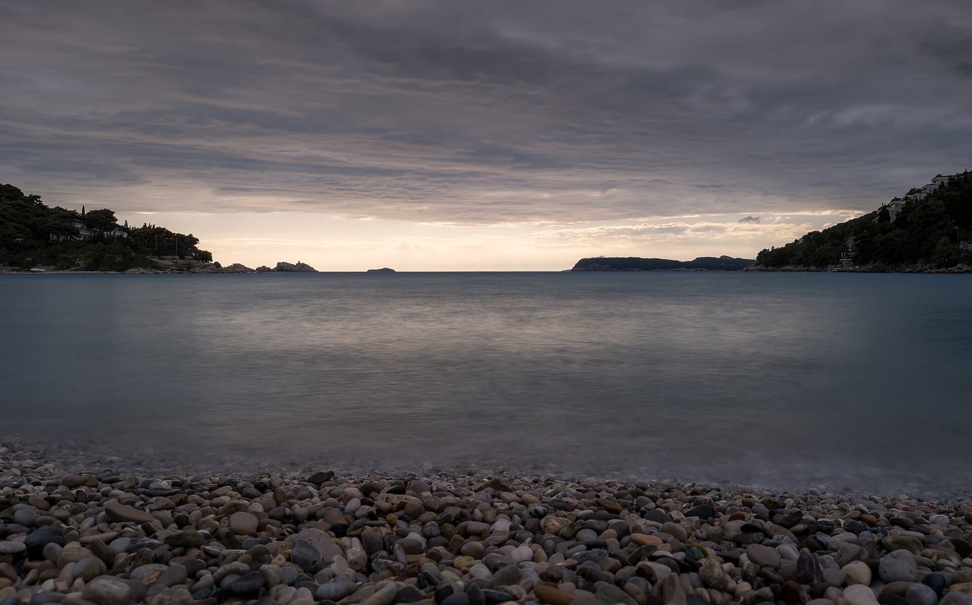 Lapad Beach at sunset with swimmers and the Dubrovnik coastline
