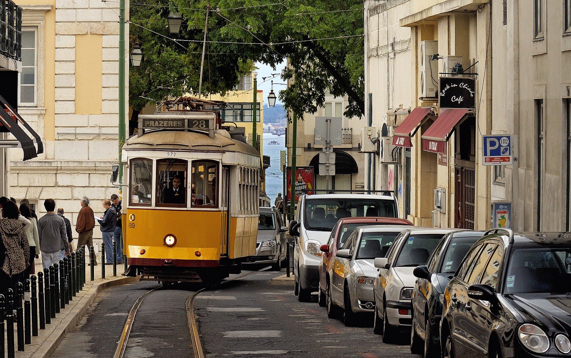 Yellow Lisbon tram 28 passing through a narrow city street